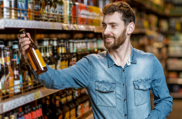 Man in a store holding a beer.